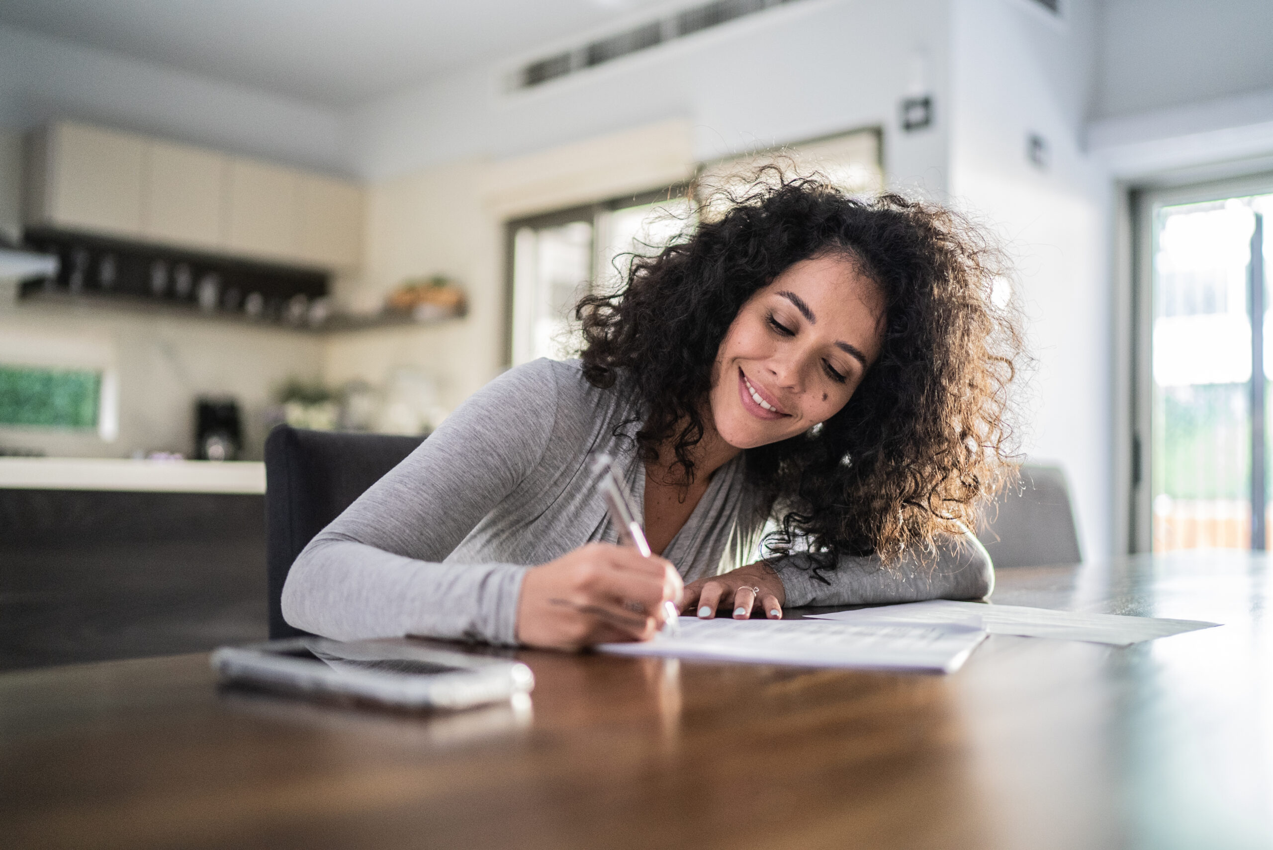 Mid adult woman filling paperwork at home